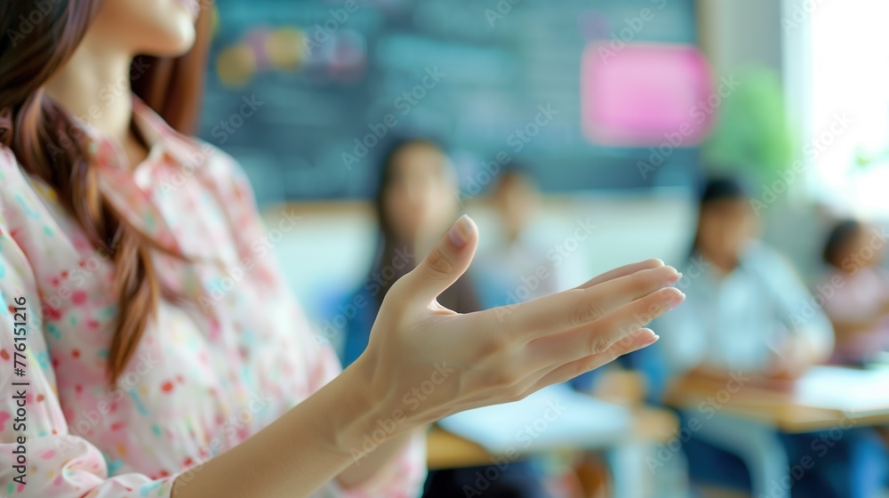 A close-up of a young female teacher's hands gesturing while she teaches in a bright and airy classroom