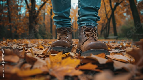 A close-up shot of leather boots walking on a path covered with fallen leaves in an autumn park photo