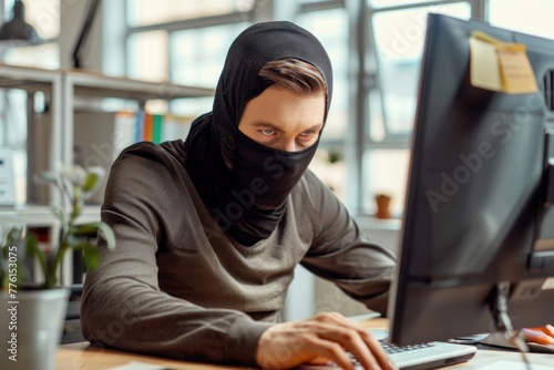 man in a black robber mask using computer in office