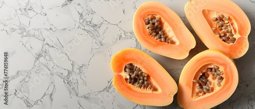   Two papayas resting on a white countertop One has been halved