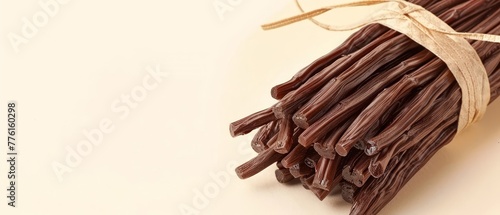  A tight shot of chocolate sticks in a bundle, topped with a warm brown ribbon, against a pristine white background