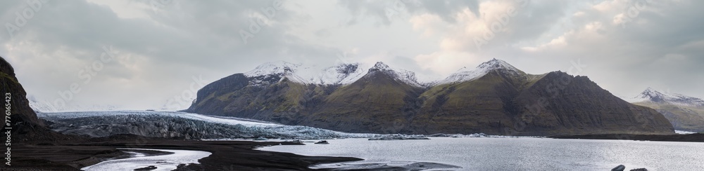 Skaftafellsjökull glacier, Iceland. Glacier tongue slides from the Vatnajökull icecap or Vatna Glacier near subglacial Esjufjöll volcano. Glacial lagoon with ice blocks and surrounding mountains.