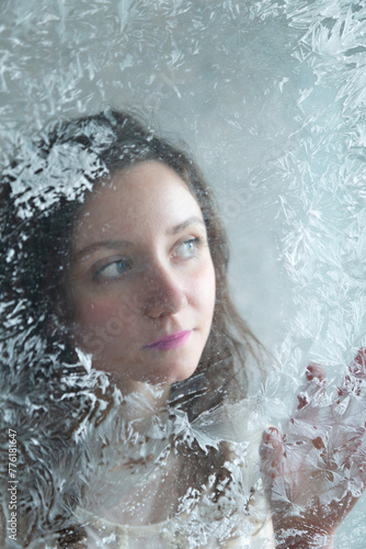 Vertical closeup pretty brunette young woman looking through frosted window