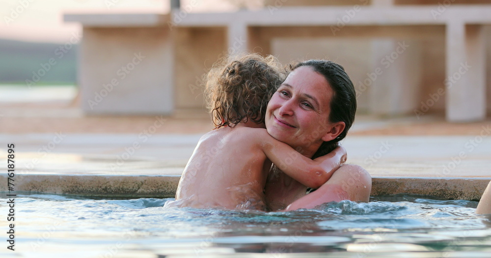Small boy hugging mother inside swimming pool water. Toddler child embracing mom Small boy hugging mother inside swimming pool water. Toddler child embracing mom