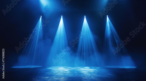 Blue spotlights illuminate an empty stage with atmospheric smoke. The anticipation of a performance in a dark theater is palpable