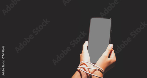 Computer, media, game, network, digital, technology, gadget  and  internet addiction. Young beautiful girl with tied hands using smartphone at night. Copy space.