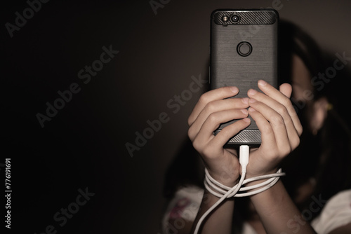 Computer, media, game, network, digital, technology, gadget  and  internet addiction. Young beautiful girl with tied hands using smartphone at night. Copy space for design. Horizontal image.