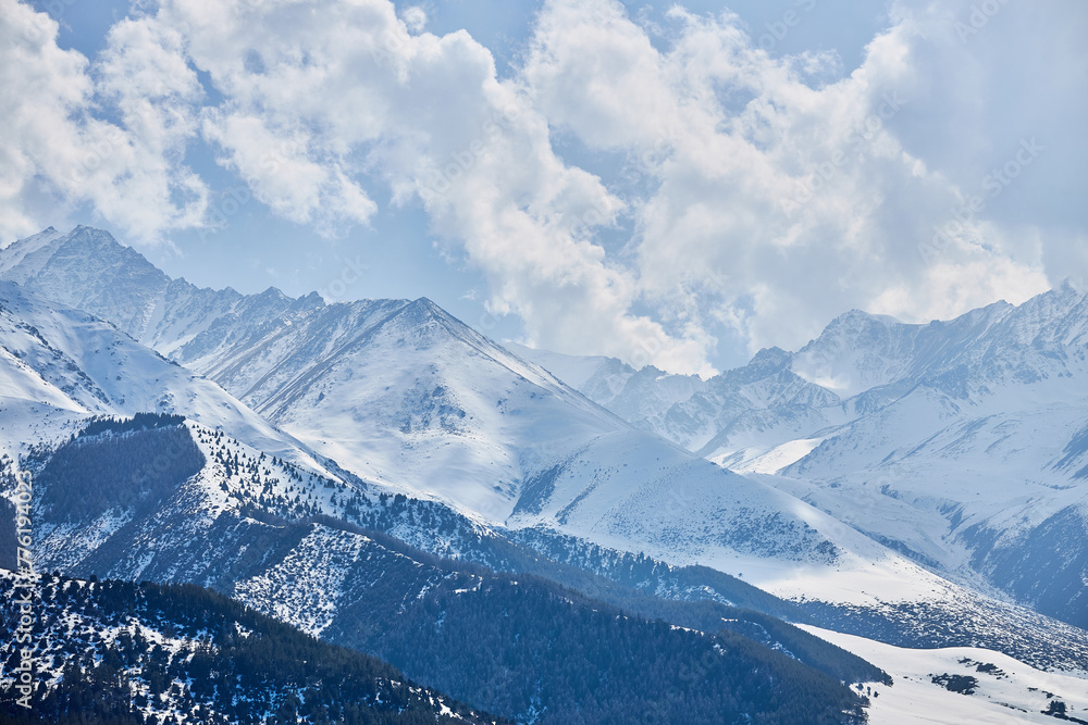 Panoramic view snow capped high mountains. Chunkurchak valley in Kyrgyzstan. Winter natural landscape, mountain range wallpaper. Epic blue sky with white beautiful clouds