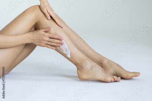 Woman applying body cream onto her smooth legs on light grey background © F8  \ Suport Ukraine