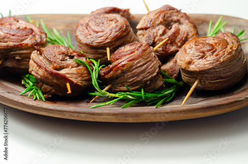 A plate of pieces of meat in the shape of roses with green herbs on top