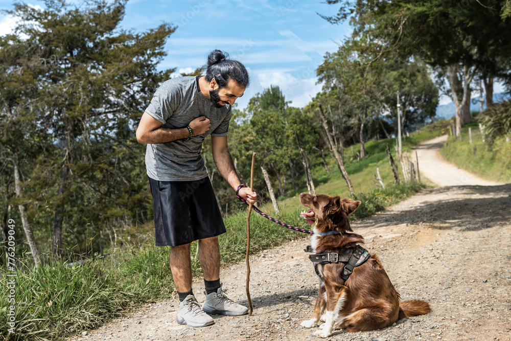 adult male mongrel training his border collie dog thanking him for learning to sit