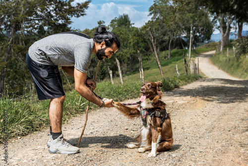 adult mestizo man training his border collie dog by teaching him how to shake hands