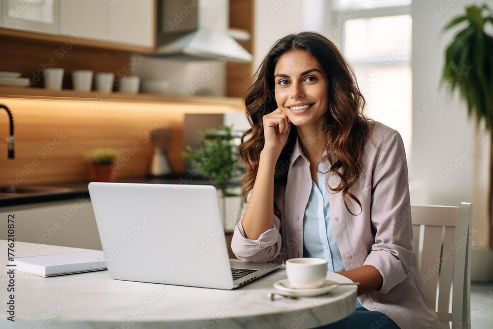 Obraz premium Female entrepreneur talking over mobile phone and looking at camera while working over laptop at home