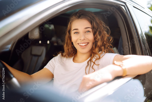 Portrait of young woman is driving a car and smiling. Automobile travel. Sharing a car. Lifestyle concept. © maxbelchenko