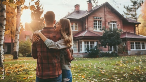 Cozy Embrace in Front of New Home.  A loving couple sharing an intimate moment, with their new home in the background.