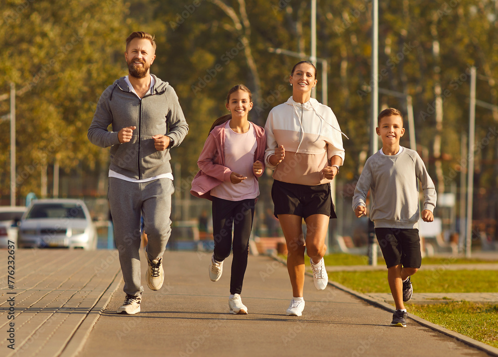 Happy healthy active family of sporty man and woman, children running together outdoors. Parents and smiling kids jogging, enjoy activity of summer physical exercise, fitness in dynamic warm-up