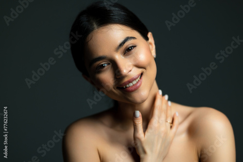 Beautiful face of young adult woman with clean fresh skin - isolated on dark background