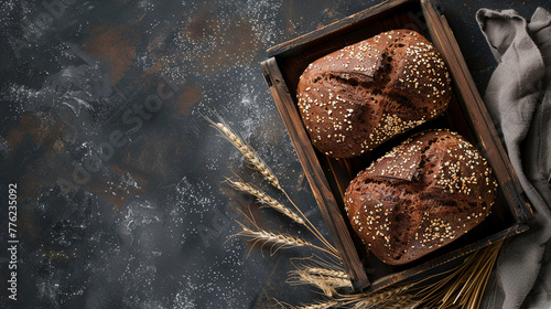 Two sourdough bread on a wooden tray with wheat and towel on dark background. Handmake bakery bread  recipe concept. Flat lay, panoramic top view. copy space. photo