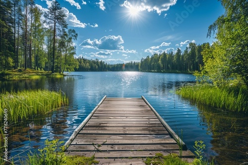 Traditional Finnish and Scandinavian view. Beautiful lake on a summer day and an old rustic wooden dock or pier in Finland. Sun shining on forest and woods in blue sky