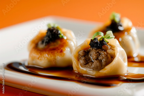 Three dumplings with sauce and garnish on a white plate