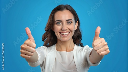 woman showing ok sign, Female hands giving a thumbs up gesture against a blue background. © Fernando Sanso