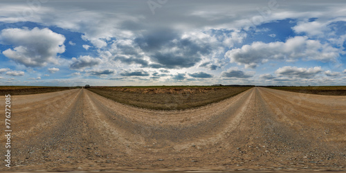 hdri 360 panorama on gravel road among fields in spring nasty day with awesome clouds in equirectangular full seamless spherical projection, for VR AR virtual reality content