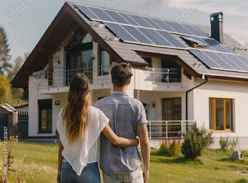 A young couple looks at their new house with solar panels on the roof, seen from behind in an eco-friendly village