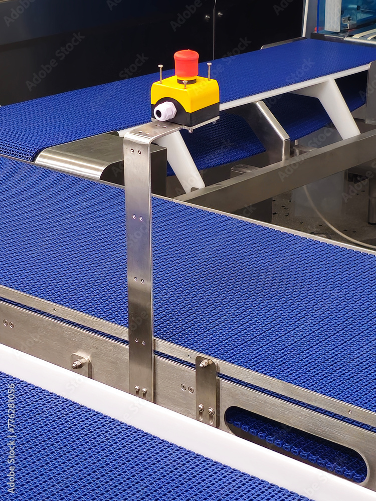 Emergency safety buttons in the stainless steel conveyor system with blue polyurethane, modular belt. Transport systems in industrial factories.