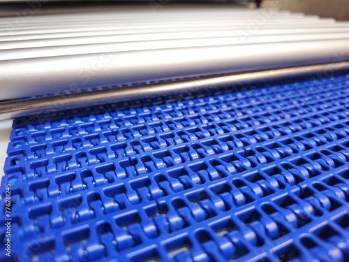 Obraz na płótnie A close-up of a blue polyurethane belt in modular industrial conveyor system connected with roller conveyor. Transport systems in industrial factories. w salonie