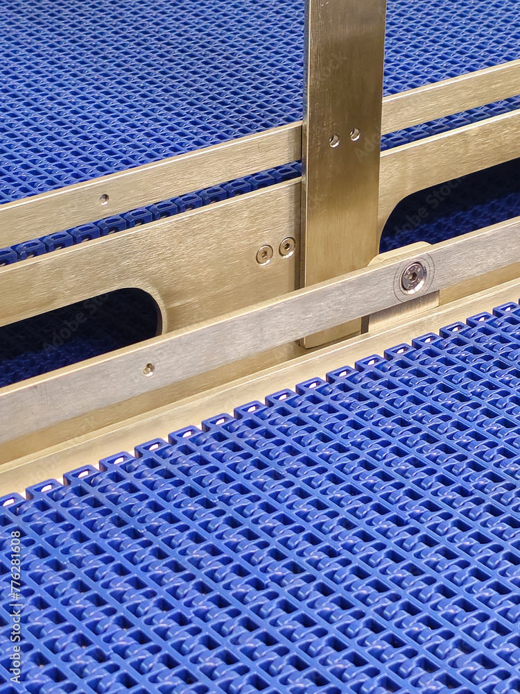 A close-up of a blue polyurethane belt in modular industrial conveyor system. Stainless steel transport systems in industrial factories.