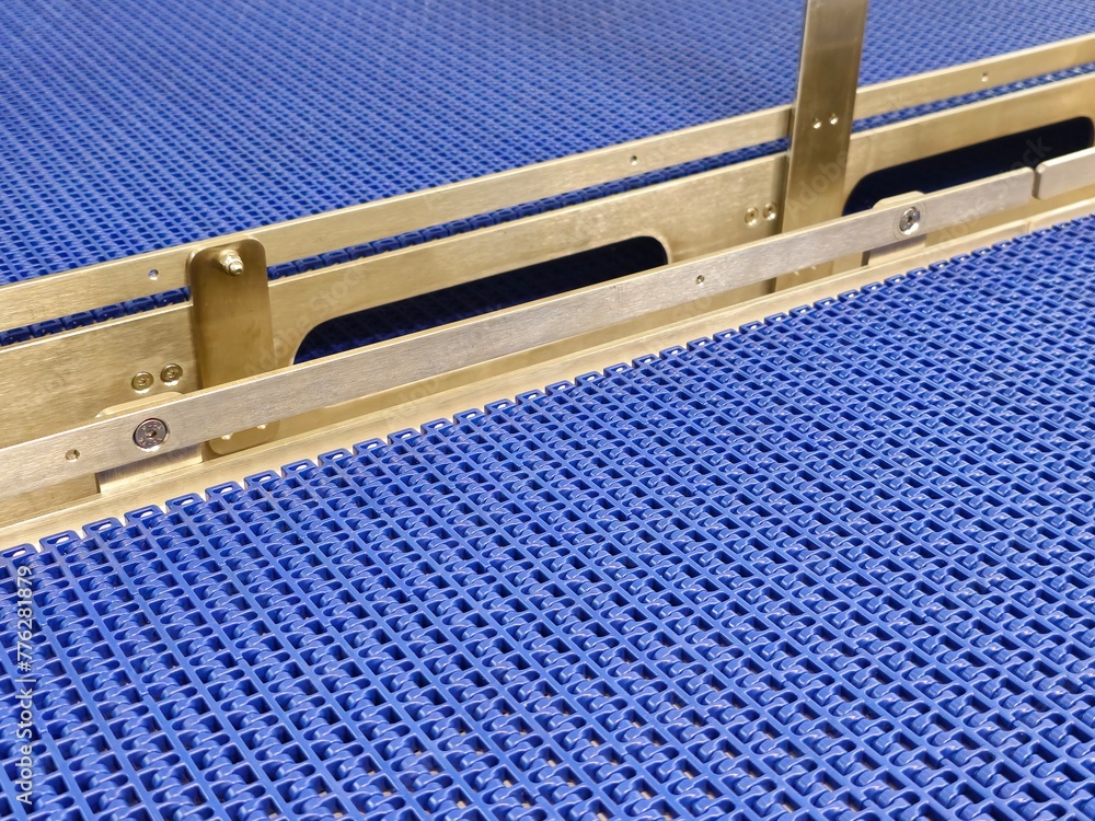 A close-up of a blue polyurethane belt in modular industrial conveyor system. Stainless steel transport systems in industrial factories.