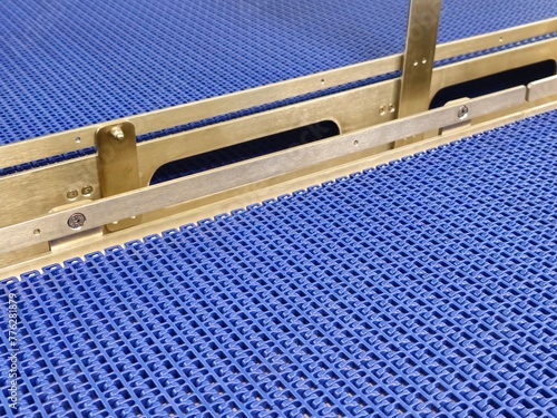 A close-up of a blue polyurethane belt in modular industrial conveyor system. Stainless steel transport systems in industrial factories.