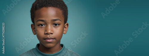 An African American Youthful Boy, Isolated On A Teal Background With Copy Space photo