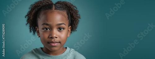 An African American Juvenile Girl, Isolated On A Teal Background With Copy Space photo