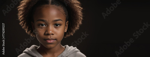 An African American Juvenile Girl, Isolated On A Dark Brown Background With Copy Space photo
