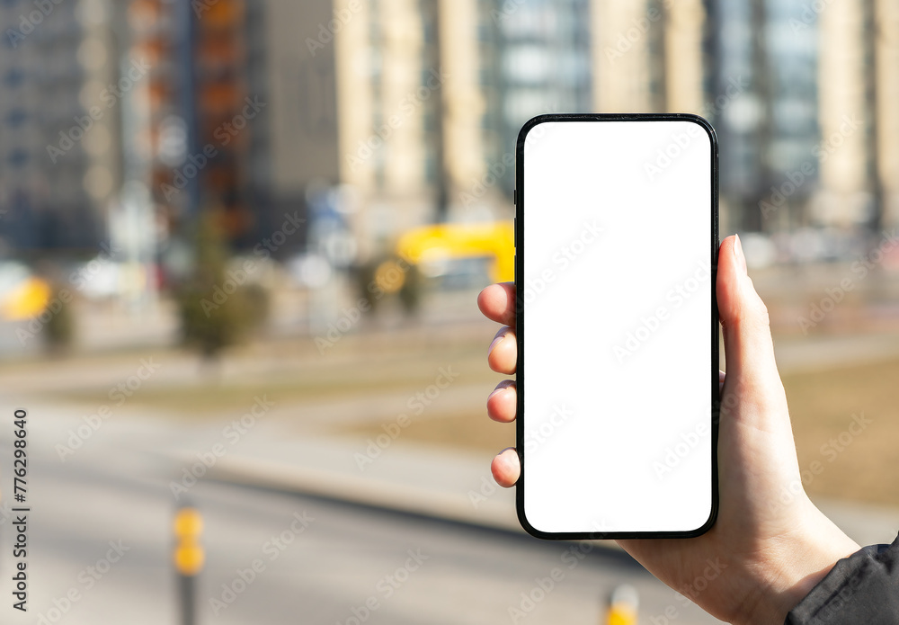 Hand holding mobile phone screen mockup, white blank smartphone display, blurred city background Hand holding mobile phone screen mockup, white blank smartphone display, blurred city background