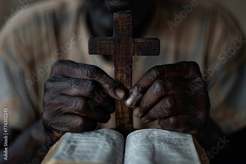 A persons hands clasping a wooden cross over an open Bible in a quiet moment of faith and prayer.
