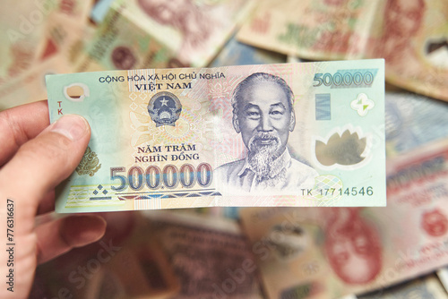 Male hand holds a fan of Vietnames Dong banknote, the currency of Vietnam. Close up Polymer Money of Vietnam. 500000 Dong or VND in male hand. In front a portrait of Ho Chi Minh. Plastic banknotes
