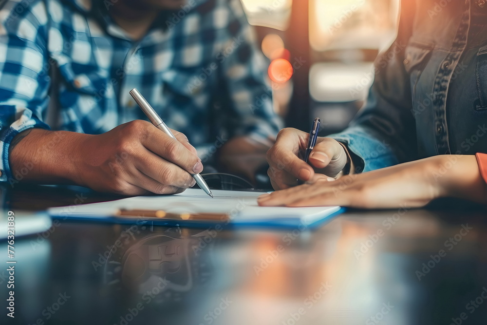 Two people signing documents sitting in front of each other Two people signing documents sitting in front of each other