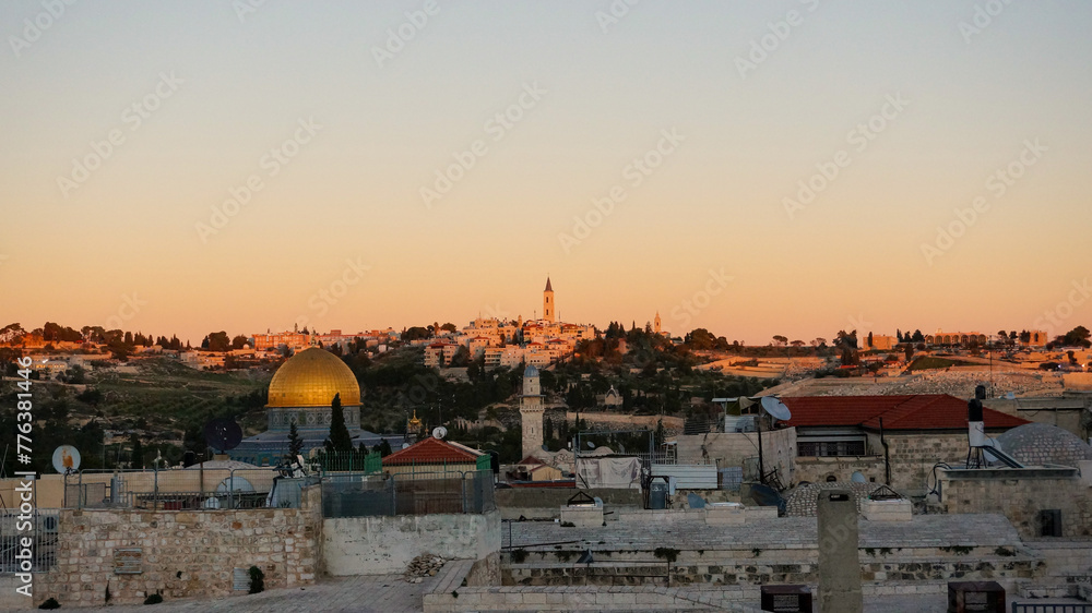 Obraz premium The golden hour casts a warm glow over Jerusalem's skyline, with the iconic Dome of the Rock shining against the ancient city's silhouette