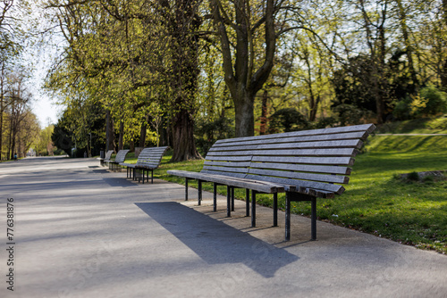 A row of park benches placed along the side of a road in urban setting