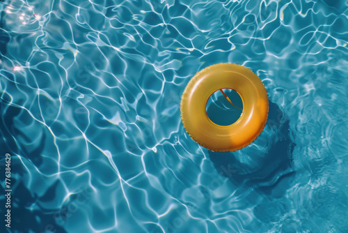 A single golden inflatable ring floats on the shimmering blue water of a swimming pool on a sunny day, symbolizing leisure and relaxation.