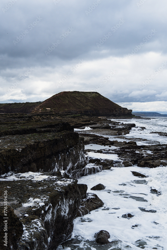 Rocky shore with an hill in the distance
