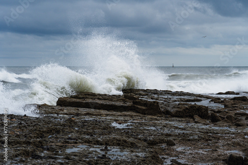 The wave crashes against rocky coastline