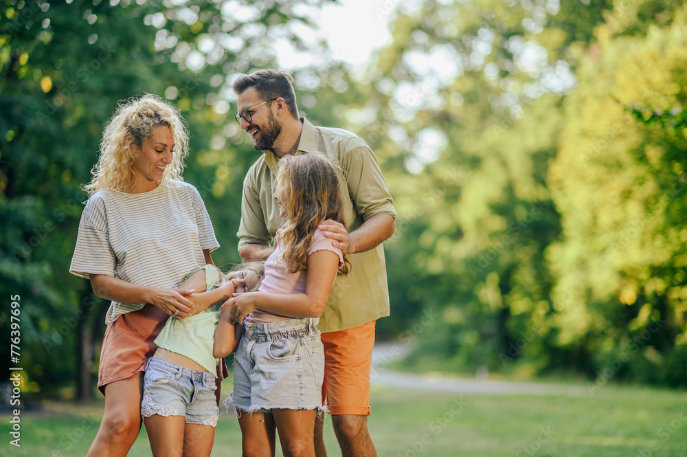 Cheerful parents hugging daughters in nature on sunny day. Cheerful parents hugging daughters in nature on sunny day.