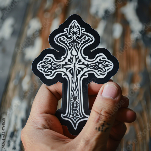 Hand Holding an Intricately Designed Cross Sticker