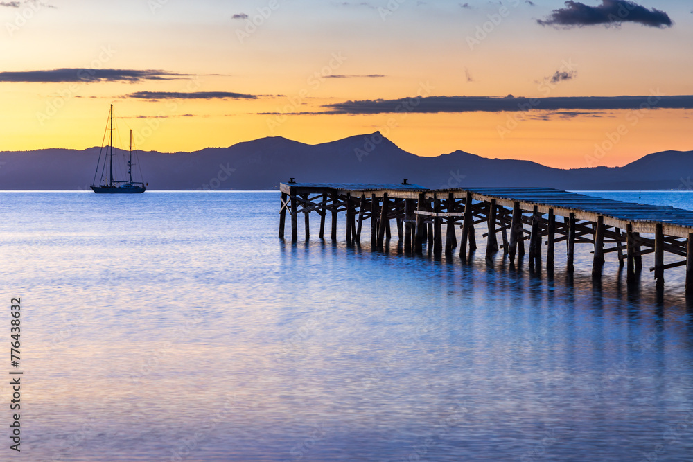 Wooden jetty at sunrise in the bay at Port d'Alcudia in Mallorca