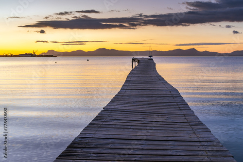 Wooden jetty at sunrise in the bay at Port d'Alcudia in Mallorca photo