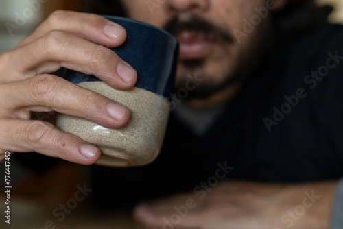 Man with beard drinks green tea in clay cup