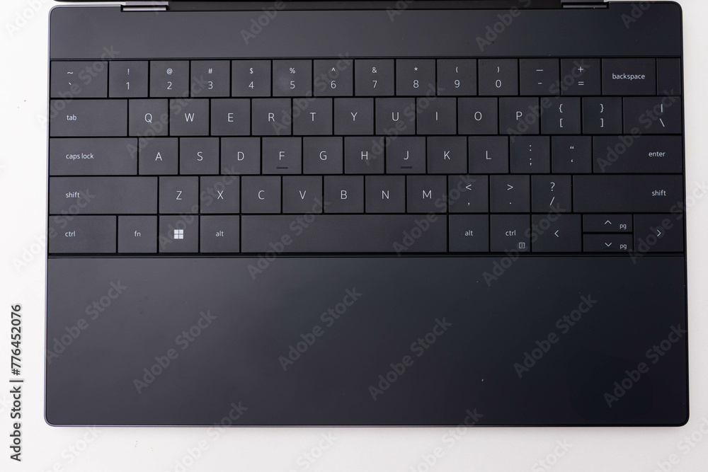 Close-up of a sleek, contemporary modern black laptop keyboard with chiclet keys, featuring a minimalist and portable design, perfect for productivity and work tool in the office
